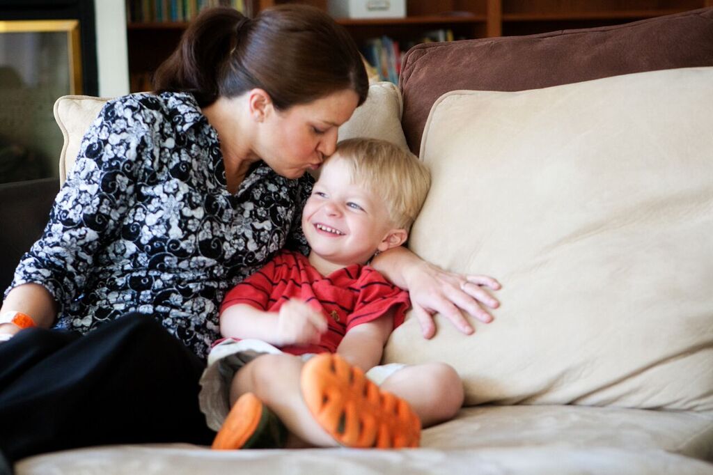 Mom kissing laughing son on his head