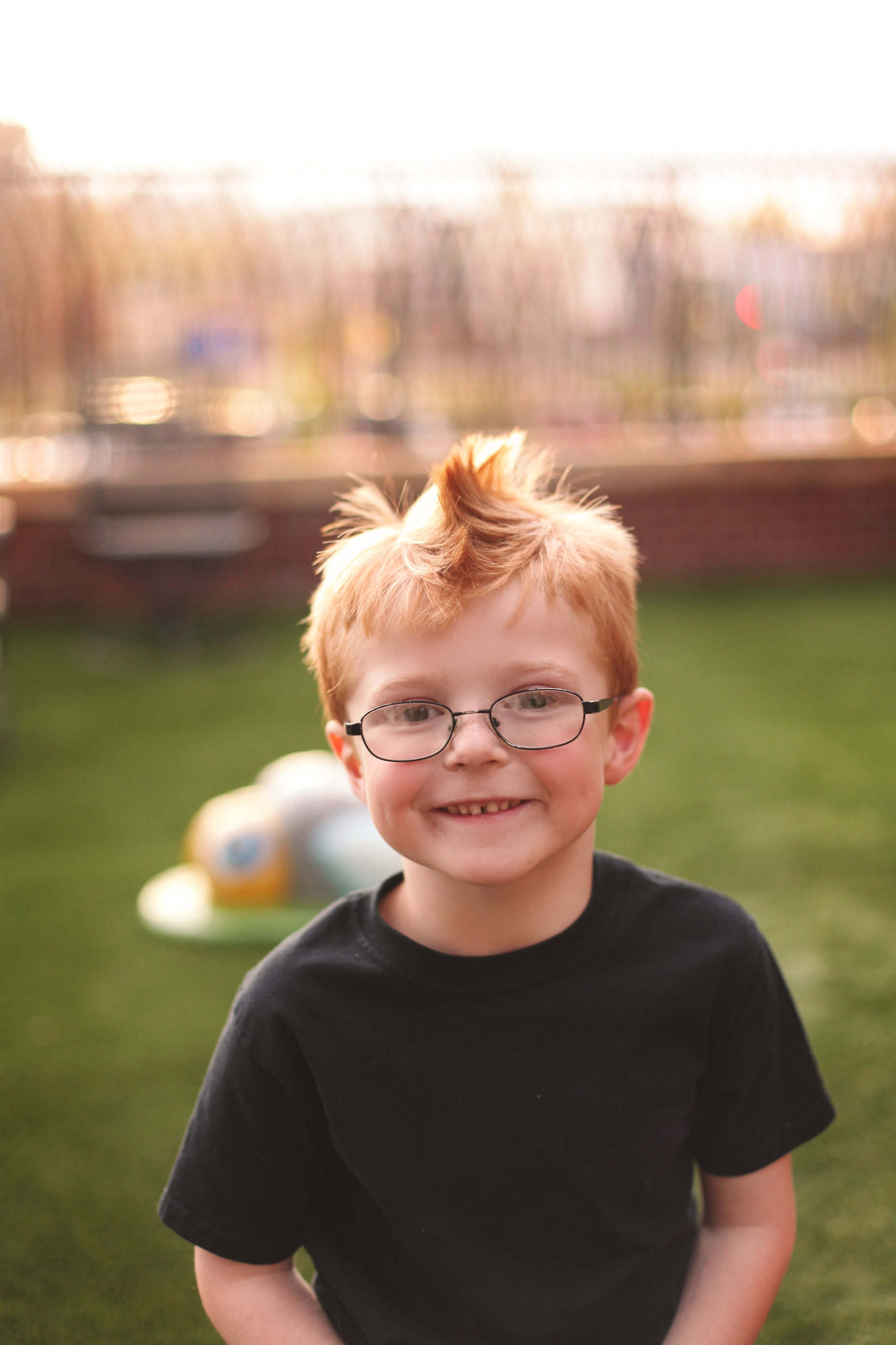 Red-haired boy in glasses smiling on the Ronald McDonald House playground