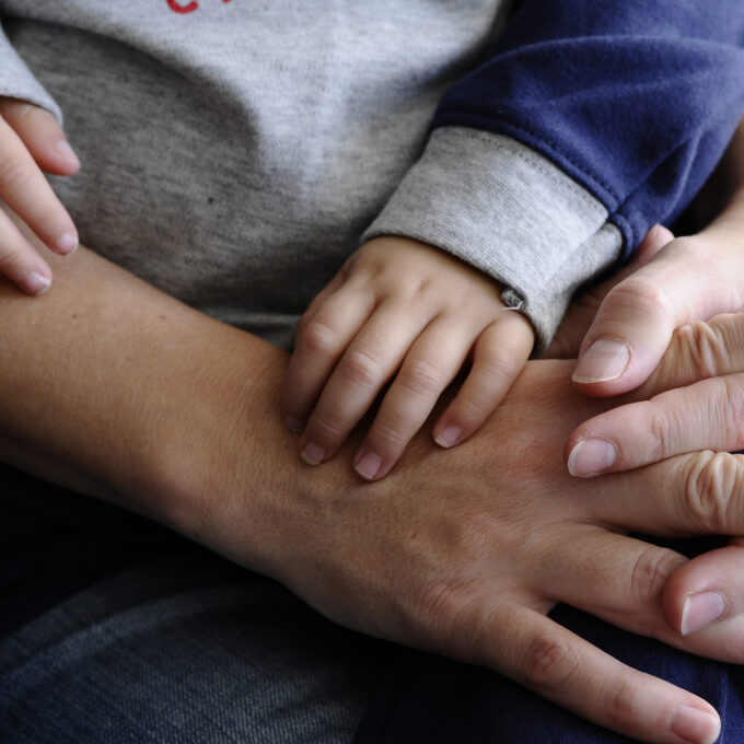 Hands of a child resting on hands of an adult