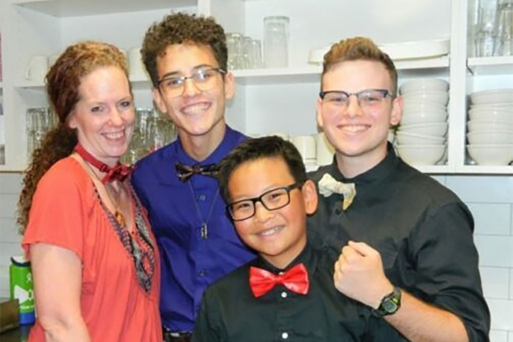 One women and three boys smiling in the kitchen at the Denver Ronald McDonald House