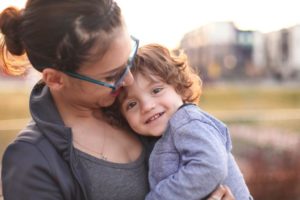 Woman cuddling a smiling young boy