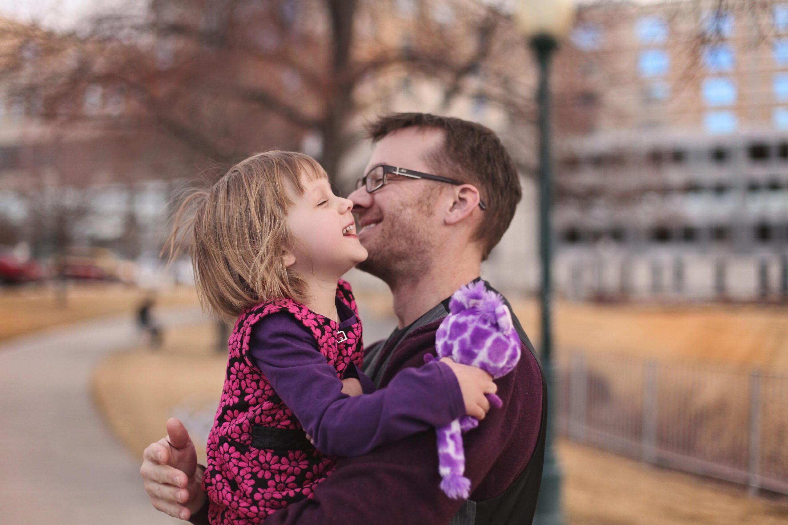 Smiling dad holding laughing young girl outdoors